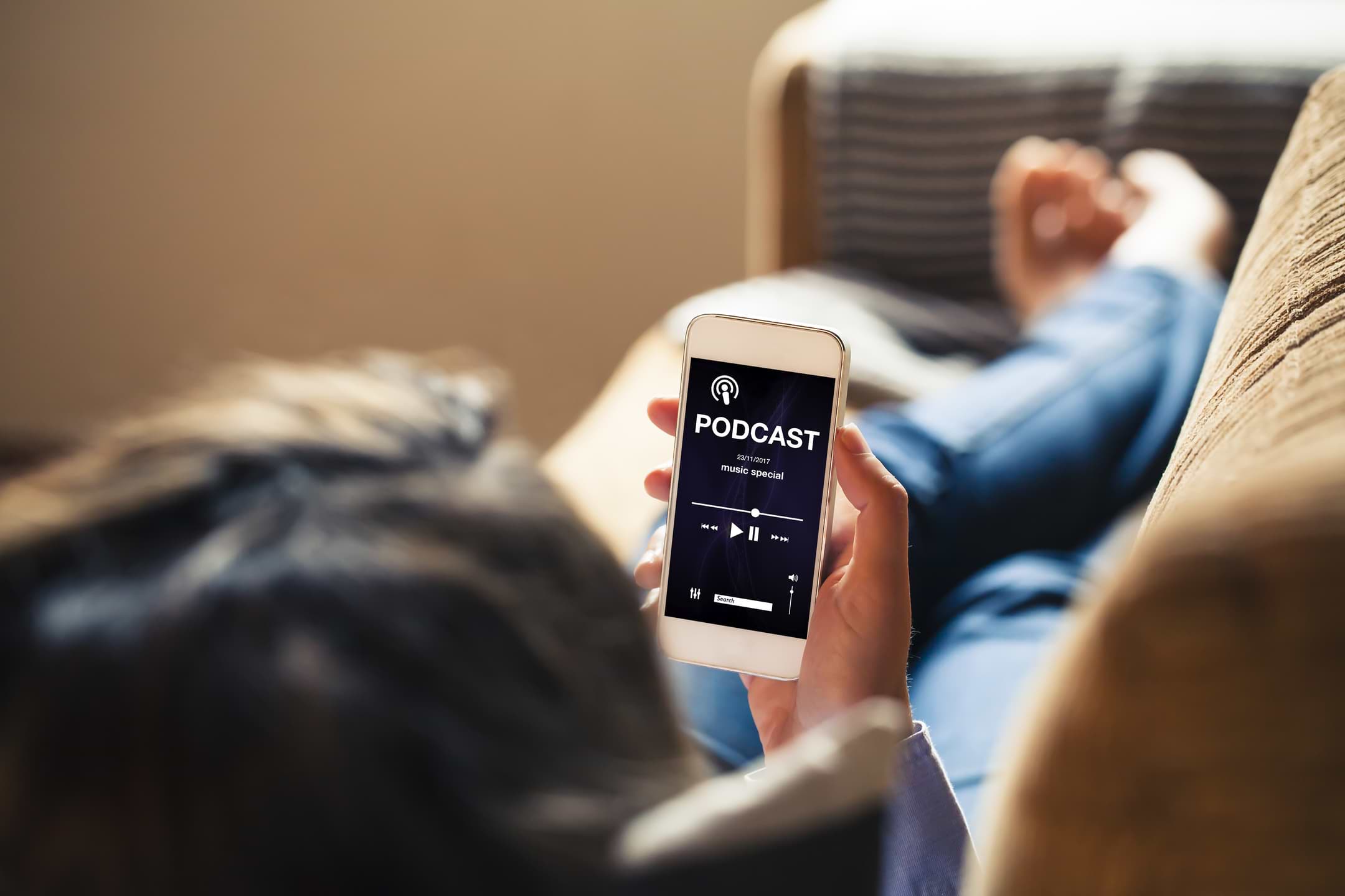 Bli proffs på privatekonomi med dessa poddar 1 Kvinna i soffa som lyssnar på podd i mobilen