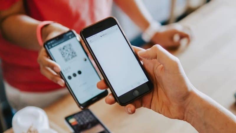 Betalningspåminnelse? Så agerar du! 1 Två personers händer som håller mobiltelefoner efter att ha fått en betalningspåminnelse